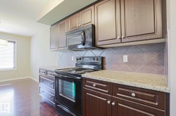 Kitchen featuring dark wood cabinetry, granite-style countertops, and a tiled backsplash - 