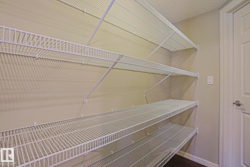 Storage area featuring multiple tiers of white wire shelving, light-toned wall paint, dark wood-finish flooring, and white trim - 6215 60 Street, Beaumont, AB - Indoor With Storage