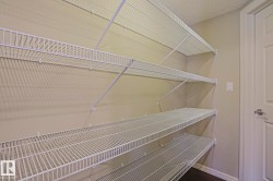 Storage area featuring multiple tiers of white wire shelving, light-toned wall paint, dark wood-finish flooring, and white trim - 