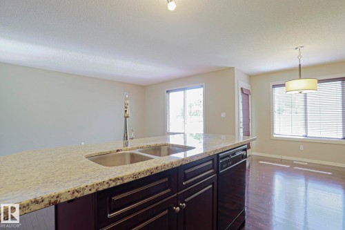 Kitchen island featuring a double basin sink, chrome pull-down faucet, and light-toned speckled countertop - 6215 60 Street, Beaumont, AB - Indoor Photo Showing Kitchen With Double Sink