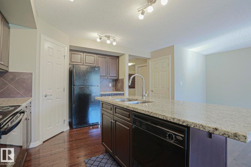 Kitchen featuring a large central island with a double basin sink and extended countertop seating - 6215 60 Street, Beaumont, AB - Indoor Photo Showing Kitchen With Double Sink
