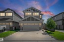 Two-story residence featuring a two-car garage with transom windows, a concrete driveway, and a stone accent facade - 1931 Westerra Lane, Stony Plain, AB 