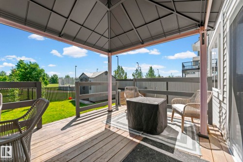 Covered outdoor deck featuring wood-finish flooring, a full-height privacy fence, and an expansive grassy area - 1931 Westerra Lane, Stony Plain, AB 