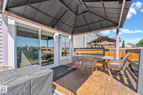 Outdoor wooden deck featuring a dark metal gazebo, privacy fencing, and sliding glass door access to the interior - 1931 Westerra Lane, Stony Plain, AB 