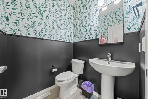Powder room with a white pedestal sink, toilet, and wood-finish flooring - 1931 Westerra Lane, Stony Plain, AB 