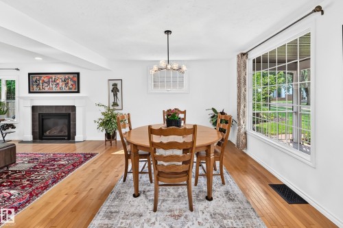 Hardwood flooring extends throughout this open-concept space, featuring a large picture window with grid detailing - 10323 138 Street, Edmonton, AB 