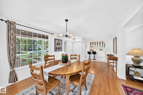 Dining area featuring wood-finish flooring, a contemporary chandelier, and a large multi-pane window - 10323 138 Street, Edmonton, AB 