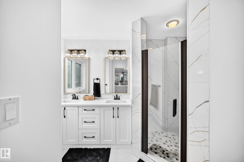 Modern bathroom featuring a dual vanity with white shaker-style cabinetry, dark hardware, and undermount sinks - 10323 138 Street, Edmonton, AB 