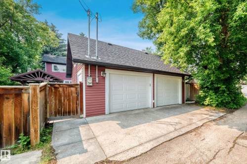 Two-car garage featuring white paneled doors, red siding, and a dark shingle roof - 10323 138 Street, Edmonton, AB 