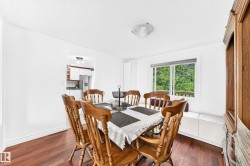 Dining area featuring wood-finish flooring, white walls, and a window with a wooded backdrop - 
