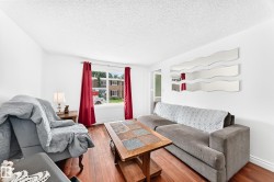 Bright living space with wood-finish flooring, white walls, and a large window - 