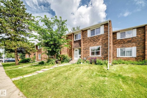 Brick exterior featuring white window frames and shutters, two levels of living space, a front entry with a small porch, a lawn, and mature trees - 191 Ridgewood Terrace, St. Albert, AB 