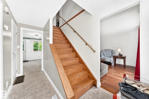 Hardwood staircase with natural wood handrail, light gray wall paint, and gray resilient flooring - 191 Ridgewood Terrace, St. Albert, AB 