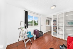 Bright room featuring wood-finish flooring, white walls, and a large window with black blinds - 