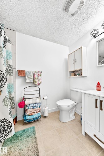 Bathroom featuring a white vanity with bronze-finish hardware, a white toilet, and light-toned tile flooring - 191 Ridgewood Terrace, St. Albert, AB 