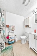 Bathroom featuring a white vanity with bronze-finish hardware, a white toilet, and light-toned tile flooring - 