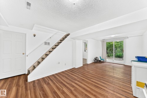 Lower level featuring wood-finish flooring, white walls, and a sliding glass door providing exterior access - 191 Ridgewood Terrace, St. Albert, AB 