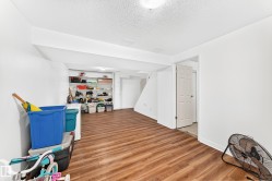 Finished basement space featuring wood-finish flooring, white walls, and built-in shelving - 
