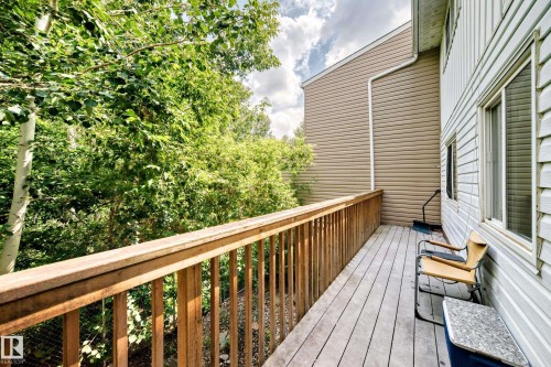 Outdoor deck featuring wood-finish railing and flooring, bordered by lush green trees - 191 Ridgewood Terrace, St. Albert, AB 