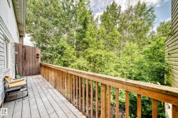 Outdoor wood-plank deck featuring a natural wood railing, a privacy wall, and verdant tree canopy - 