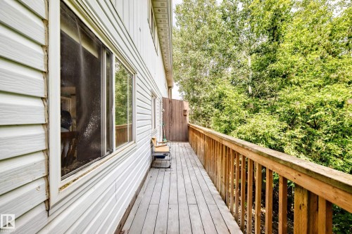 Wood-finish deck with natural wood railing, white siding exterior, and mature tree backdrop - 191 Ridgewood Terrace, St. Albert, AB 