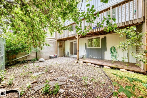 Rear exterior featuring a ground-level patio, upper-level wood deck, sliding glass door, and a basement window - 191 Ridgewood Terrace, St. Albert, AB 