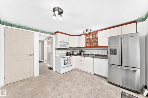 Kitchen featuring white cabinetry with wood-finish trim, a stainless steel French door refrigerator, and a white electric range - 191 Ridgewood Terrace, St. Albert, AB 