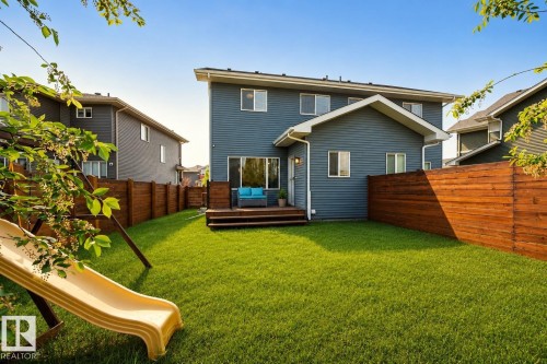 Expansive green lawn with a wood plank privacy fence and a rear deck - 70 James Crescent, St. Albert, AB 
