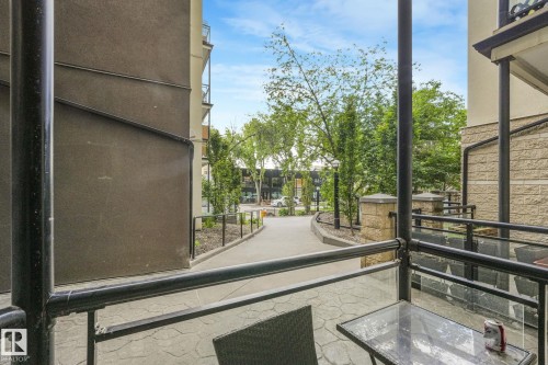 Private patio space featuring a stamped concrete surface and black metal railings with clear panel inserts - 131 10407 122 Street, Edmonton, AB 