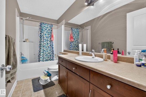 Bathroom featuring a combination shower/bathtub with a white surround, a toilet, and a vanity with a single basin sink - 547 Leger Way, Edmonton, AB 