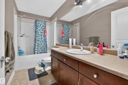 Bathroom featuring a combination shower/bathtub with a white surround, a toilet, and a vanity with a single basin sink - 