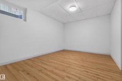 Bright interior space featuring wood-finish flooring, white painted walls, a drop ceiling, and a flush-mount ceiling light fixture - 