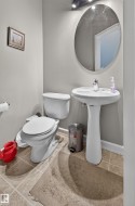 Bathroom featuring a pedestal sink, oval mirror, and tile flooring - 