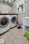 Dedicated laundry area featuring a front-loading washer and dryer, utility sink, window, wire shelving, and wood-finish countertop - 