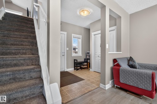 Foyer entry featuring ceramic tile flooring, a built-in closet with bi-fold doors, and a window with white trim - 547 Leger Way, Edmonton, AB 