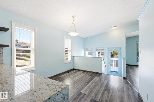 Open-concept living area featuring wood-finish flooring, a vaulted ceiling, and multiple windows with blinds - 14908 137 Street, Edmonton, AB 