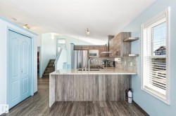 Contemporary kitchen featuring wood-finish cabinetry, stainless steel appliances, and a stone countertop with matching backsplash - 