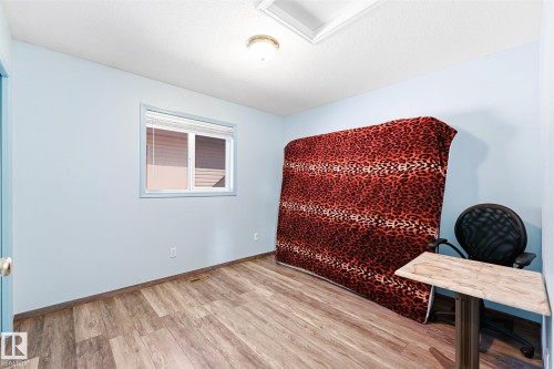 Room featuring wood-finish flooring, light blue wall paint, and a window with blinds - 14908 137 Street, Edmonton, AB 