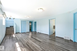 Spacious interior featuring wood-finish flooring, light blue painted walls, multiple light blue doors, and ceiling-mounted light fixtures - 
