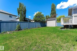 Fenced backyard featuring a storage shed, a raised deck with white railings, and a planting bed along the perimeter - 