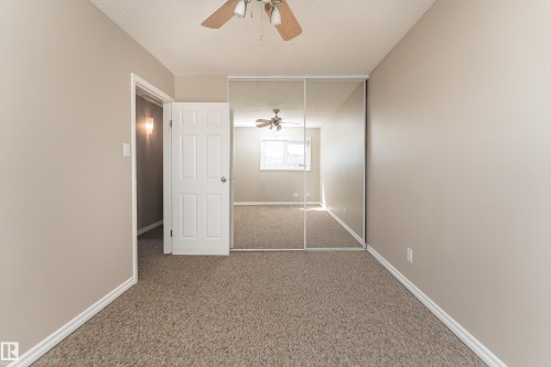 Neutral-toned room featuring wall-to-wall carpeting, white baseboards, and a ceiling fan with integrated lighting - 16B Callingwood Court, Edmonton, AB 
