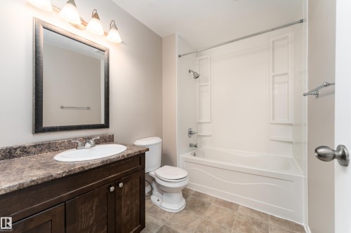 Bathroom featuring a vanity with a dark wood-finish cabinet, oval undermount sink, and a multi-tone countertop - 16B Callingwood Court, Edmonton, AB 