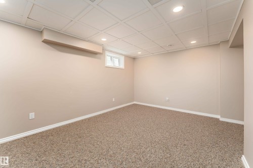 Versatile room featuring plush carpeting, neutral wall finishes, a drop ceiling with recessed lighting, and a white-trimmed window - 16B Callingwood Court, Edmonton, AB 