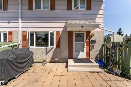 Front entrance with a white door, overhead awning, and exterior lighting - 16B Callingwood Court, Edmonton, AB 
