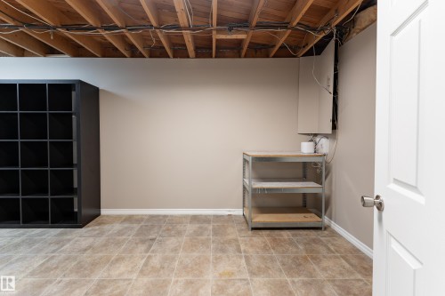 Unfinished ceiling joists, neutral wall paint, and square floor tiles - 16B Callingwood Court, Edmonton, AB 