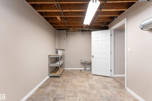 Utility space featuring tiled flooring, painted walls, overhead lighting, and built-in cabinetry - 16B Callingwood Court, Edmonton, AB 