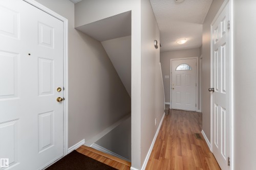 Entryway featuring wood-finish flooring, light gray wall paint, and white trim - 16B Callingwood Court, Edmonton, AB 