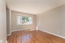 Bright interior room featuring wood-finish flooring, neutral-toned walls, and white baseboards - 16B Callingwood Court, Edmonton, AB 