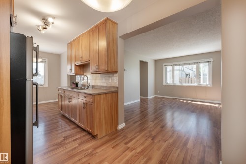 Kitchen featuring wood cabinetry, a stainless steel sink, and light-toned countertops - 16B Callingwood Court, Edmonton, AB 