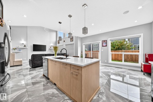 Central kitchen island featuring light wood-finish cabinetry, a white countertop, and a black gooseneck faucet - 8710 Mayday Lane, Edmonton, AB 